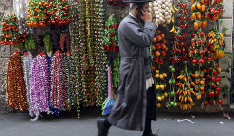 epa01871789 An ultra-Orthodox Jewish man on his telephone passes decorations for the Sukkot holiday on display on a Jerusalem sreeet on 23 September 2009. Sukkot, or the week-long Feast of Tabernacles, commemorates the Israelites wandering the the desert for 40 years. EPA/MIRIAM ALSTER ISRAEL OUT